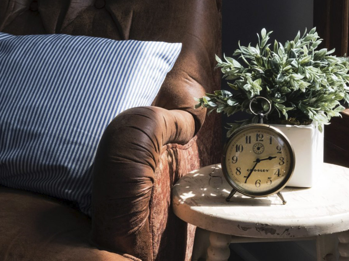 A clock sitting on top of a table next to a chair.