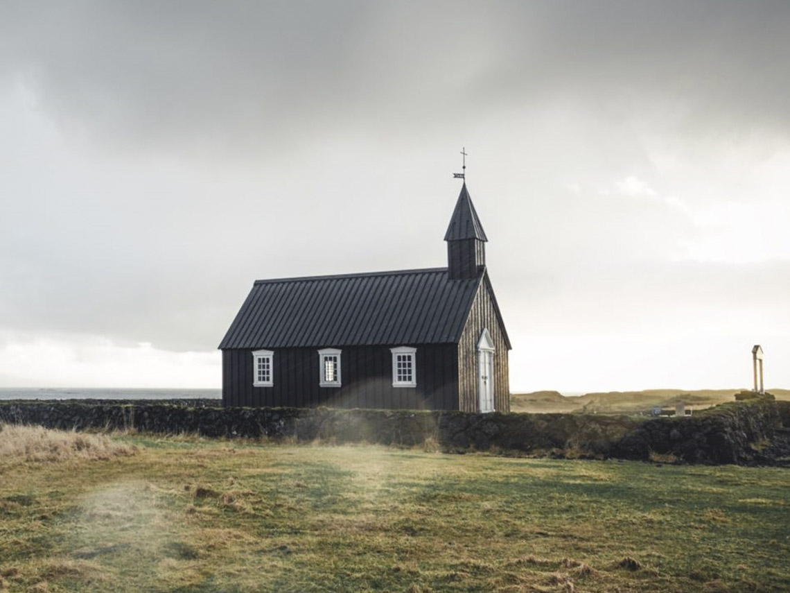 A black church with a steeple and cross on top.