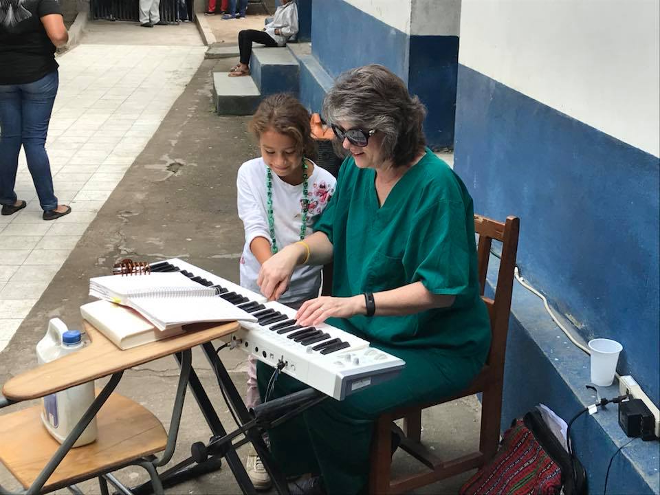 A woman sitting next to another person playing an instrument.