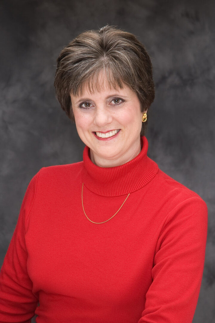 A woman in red shirt smiling for the camera.