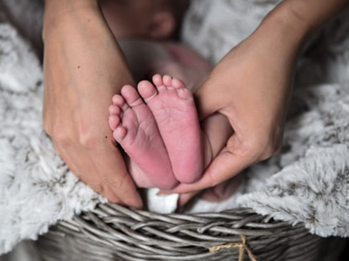 A person holding their baby 's foot in the basket.