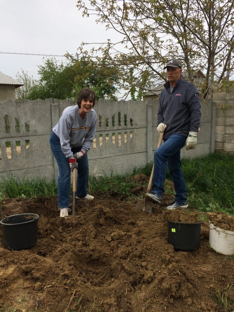 Two people are digging in the dirt with shovels.