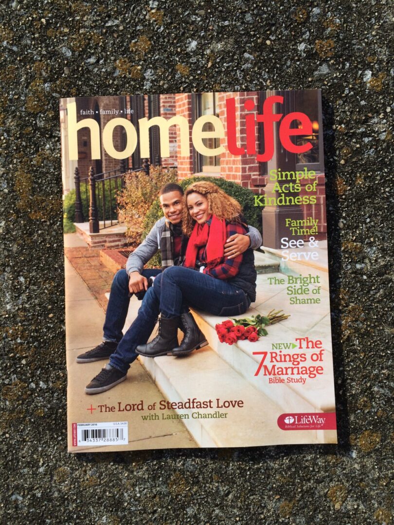 A couple sitting on the ground with a magazine.