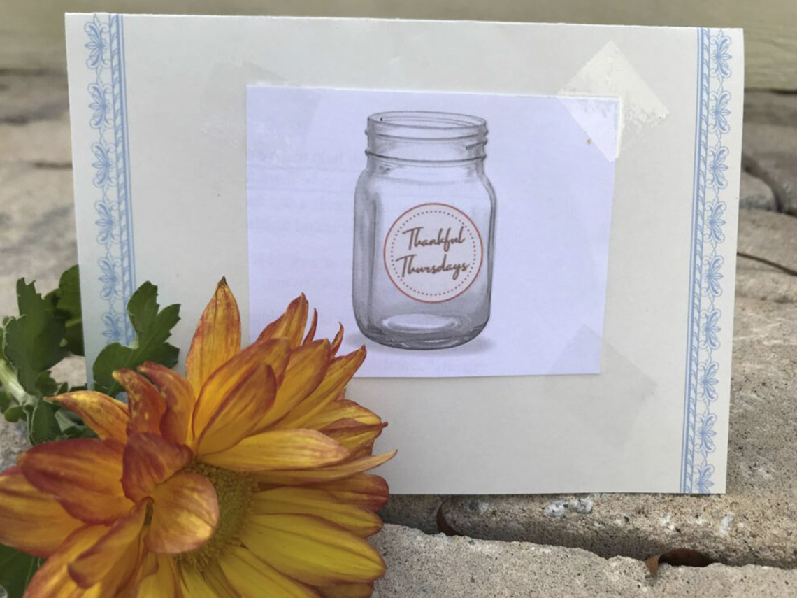 A mason jar sitting next to a flower.