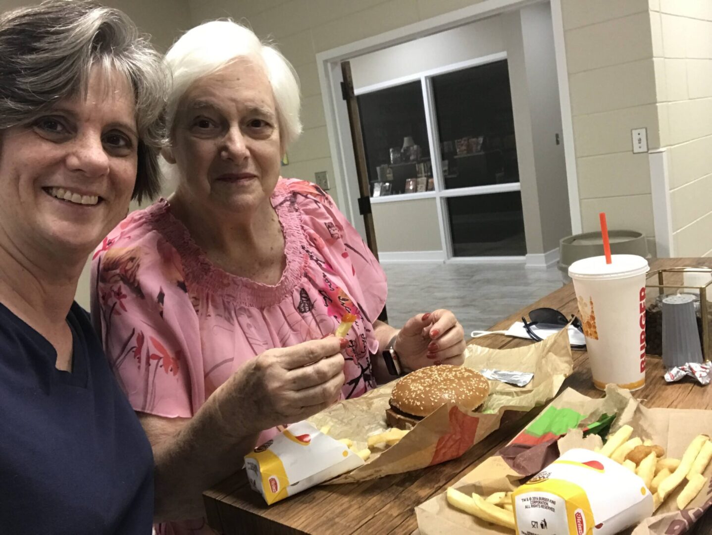 Two women sitting at a table with some food.