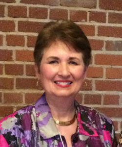 A woman standing in front of a brick wall.