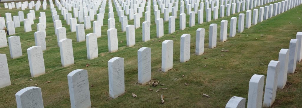 A field of white tombstones in the grass.