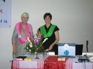 Two women standing next to a table with flowers.