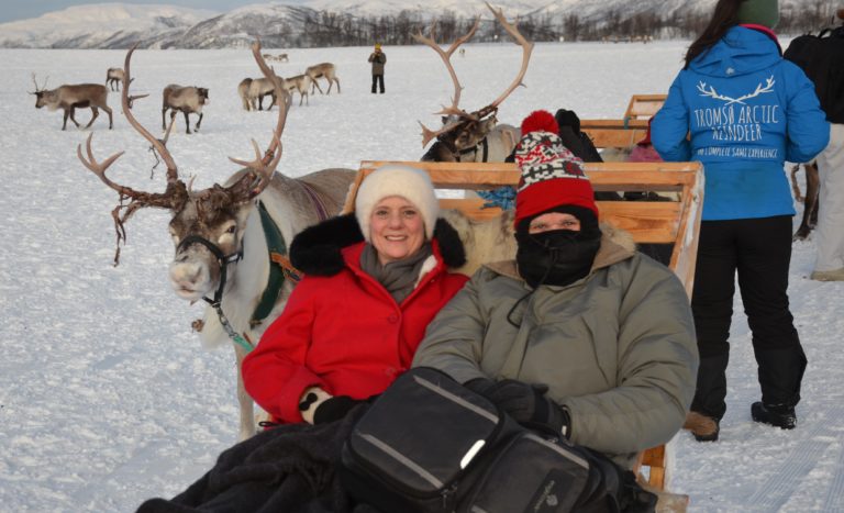 Two people sitting on a bench with luggage.