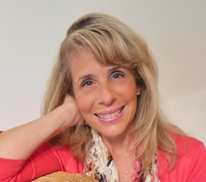 A woman with blonde hair and pink shirt smiling.