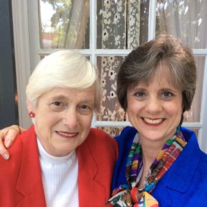 Two women standing next to each other in front of a window.