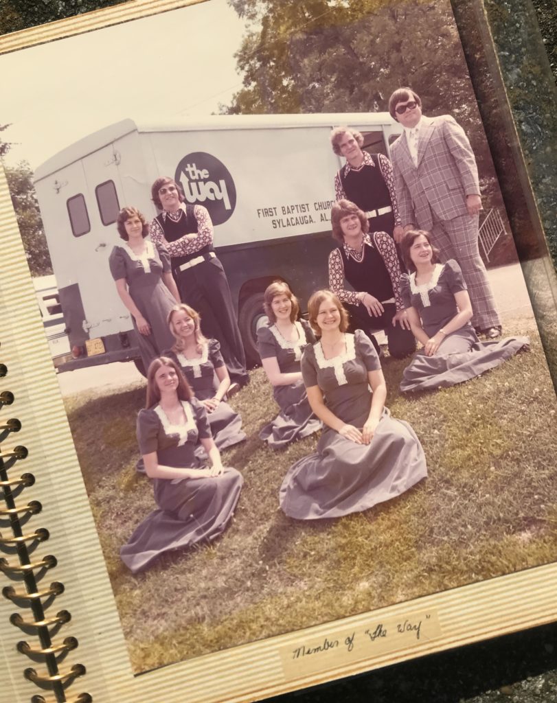 A group of people sitting in front of a white van.