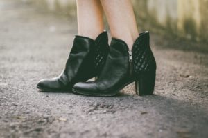 A person wearing black boots standing on the street.