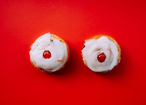 Two donuts with white frosting and a cherry on top.