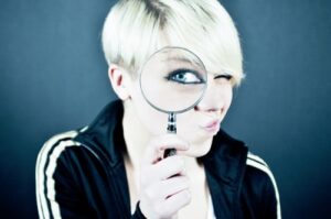 A woman holding a magnifying glass up to her eye.