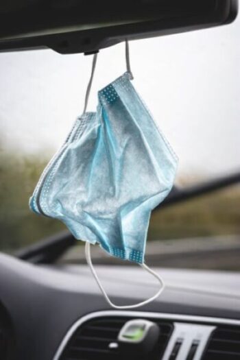 A blue mask hanging from the side of a car window.