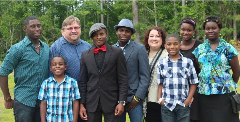 A group of people standing together in front of trees.