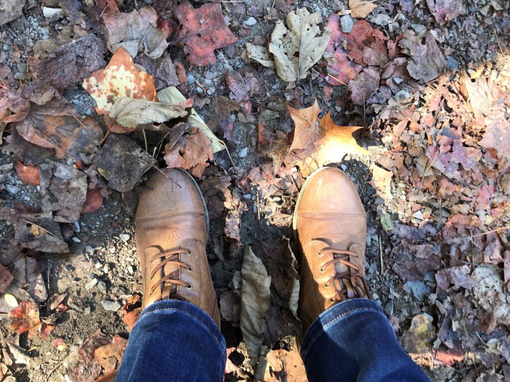 A person standing on the ground with shoes and leaves