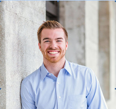 A man in blue shirt leaning against wall.