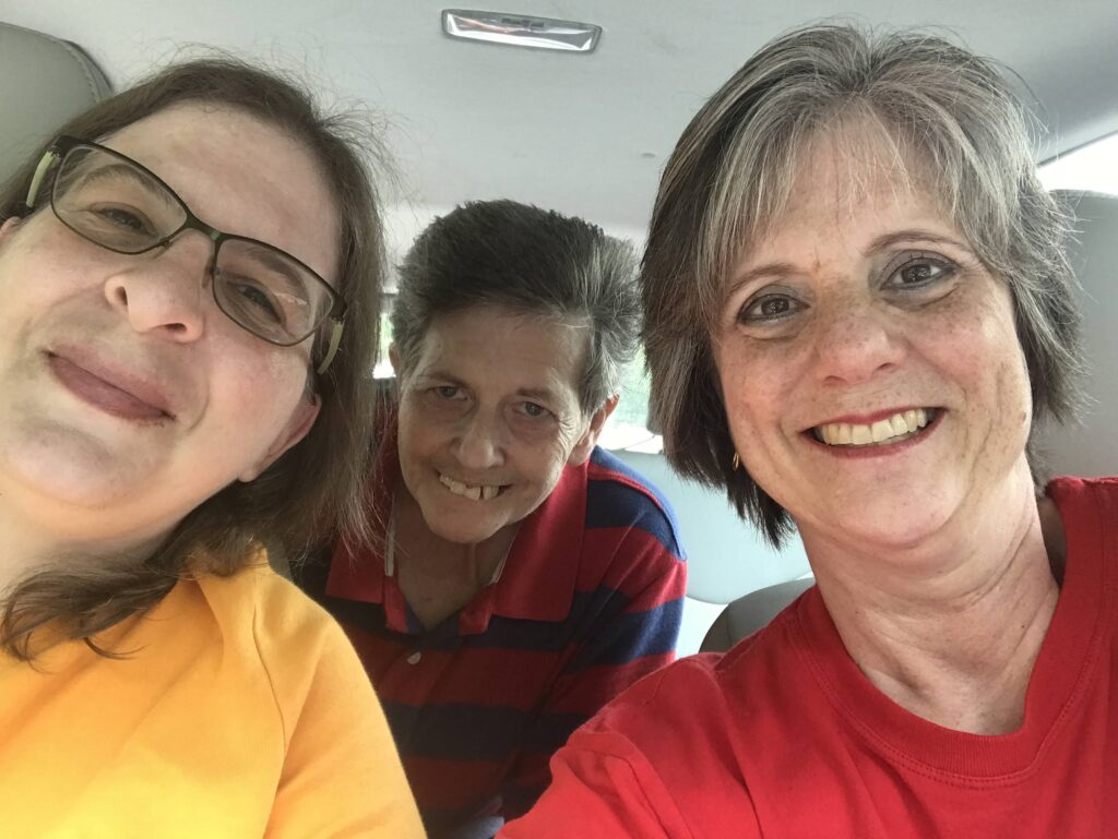 Three women in a car smiling for the camera.