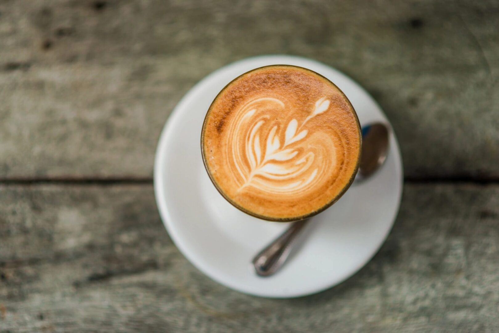 A cup of coffee on top of a white plate.