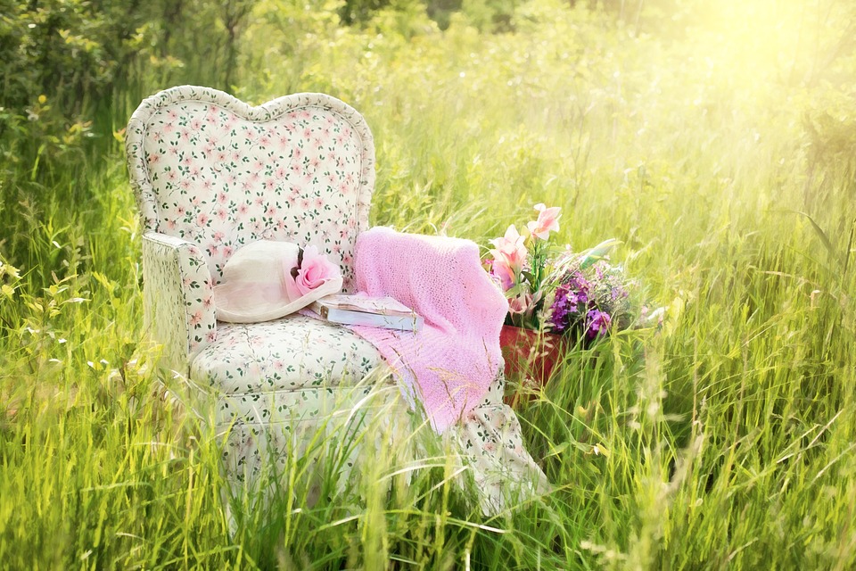 A chair in the grass with flowers on it
