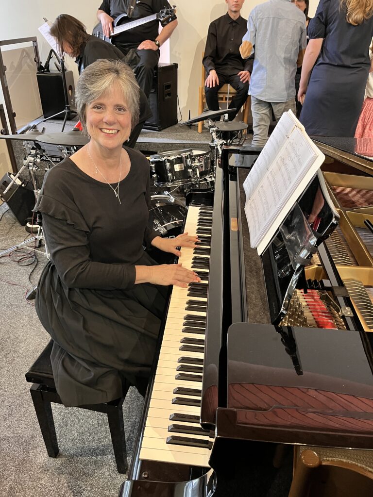 A woman sitting at the piano smiling for the camera.