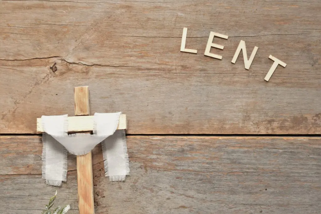 A wooden cross with letters spelling out the word lense.