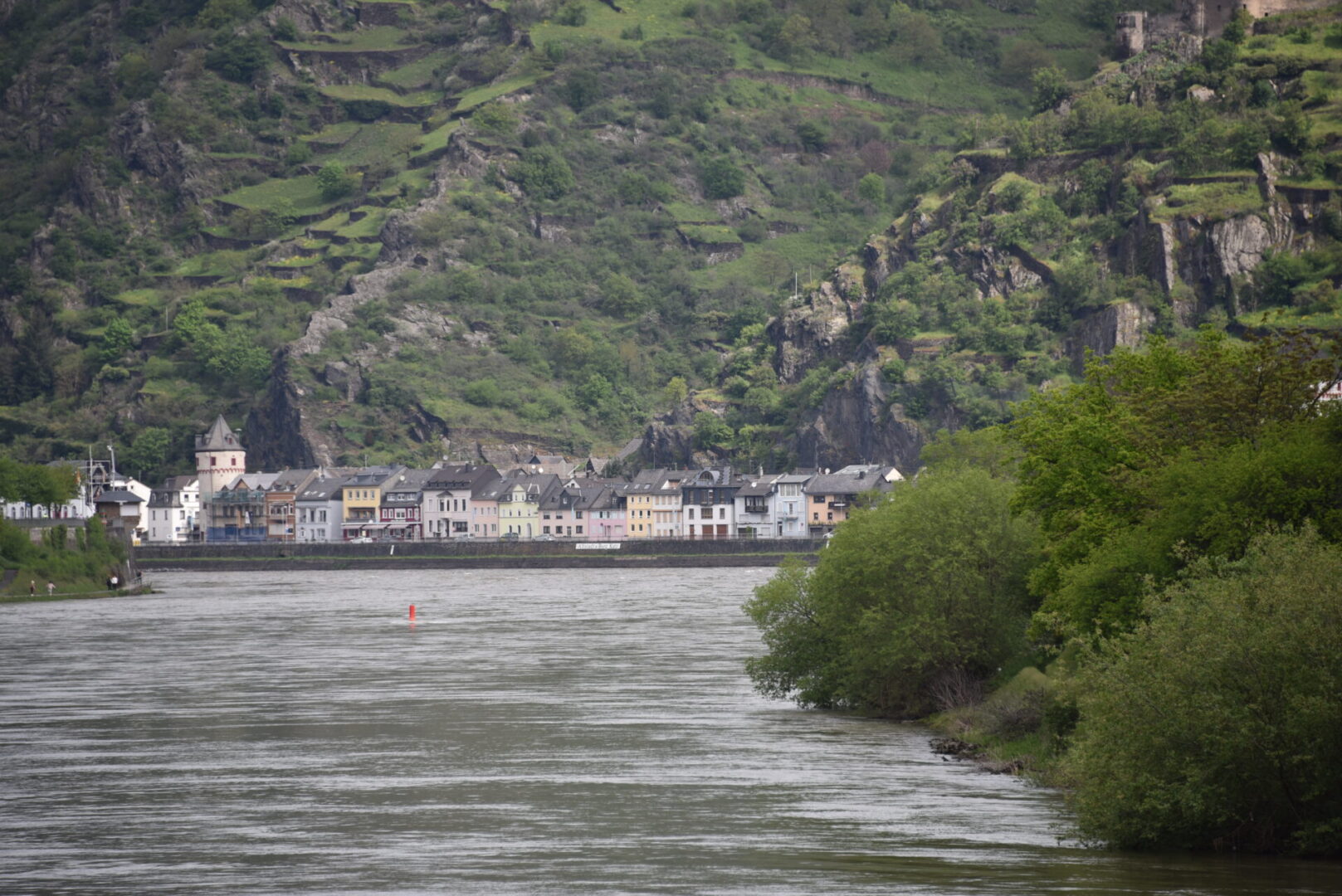 A river with houses on it and mountains in the background.