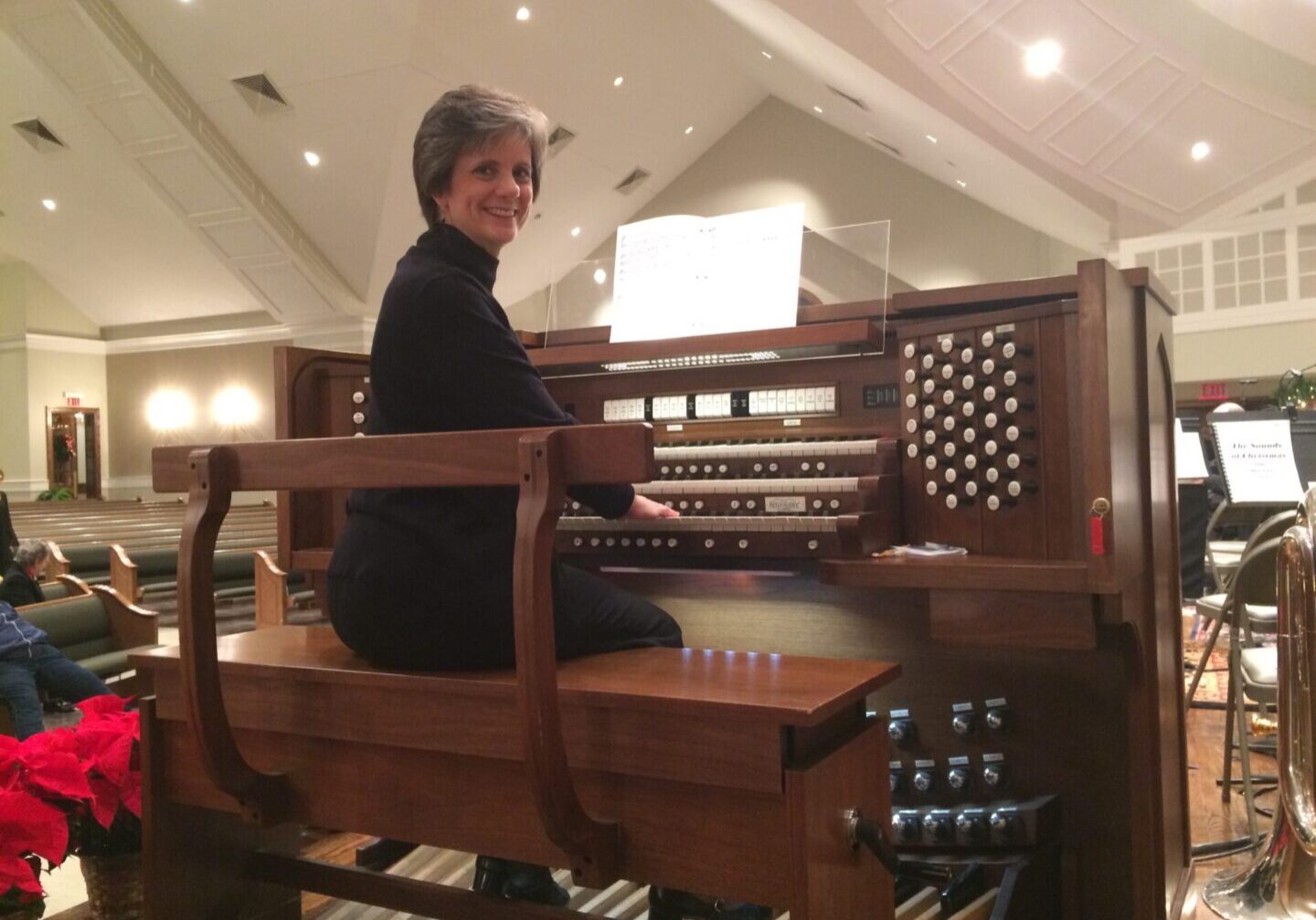 A woman sitting at the organ in a church.